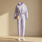 Kaelo women's cropped hoodie and jogger lounge set in soft lilac fleece, front view styled with a beige crossbody bag and white sneakers.