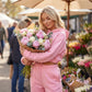 Kaelo premium fleece cropped hoodie and jogger set in pink, worn by a woman holding a bouquet of flowers in a sunny outdoor market.