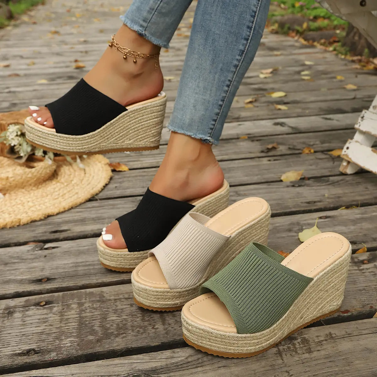 Kaelo knitted espadrille wedge sandals displayed in black, beige, and olive green, shown on feet with blue denim jeans on a wooden boardwalk.