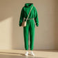 Kaelo women's cropped hoodie and jogger set in emerald green fleece — front view styled with a crossbody bag and sneakers.