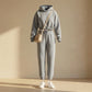 Kaelo women's cropped hoodie and jogger set in heather grey fleece — front view styled with a beige crossbody bag and white sneakers.