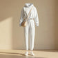 Kaelo women's cropped hoodie and jogger set in white fleece, styled with a beige cross-body bag and sneakers — front view showing the adjustable waist toggle.