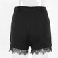 Back view of Kaelon black high-waisted shorts featuring elegant floral lace trim along the hem, displayed on a mannequin against a white studio background.