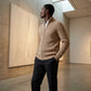 Kaelon mens ribbed zip cardigan in beige, styled with a white shirt and dark trousers in a modern gallery — three-quarter view showing the stand collar.