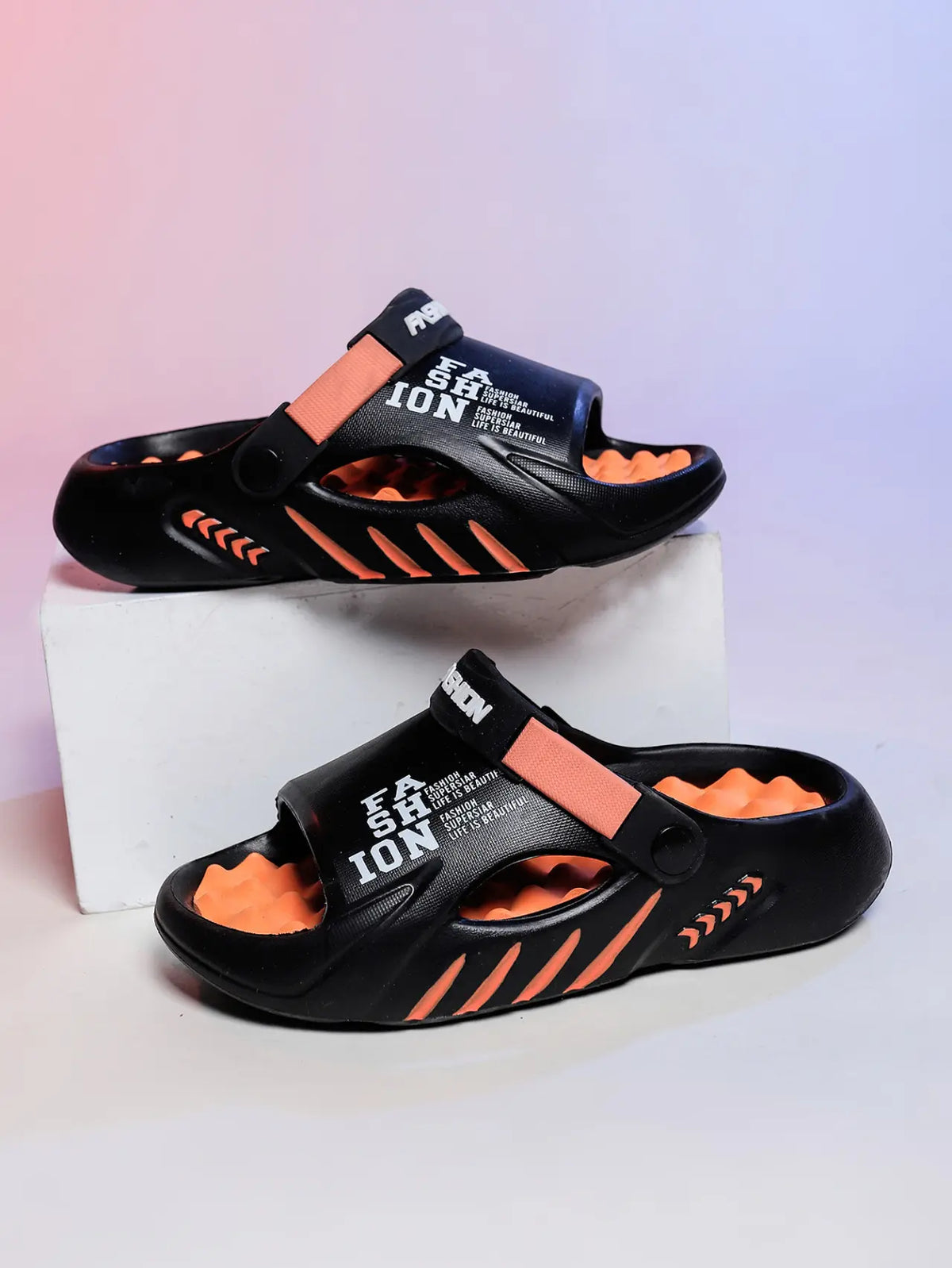 Kaelos black EVA slide sandals with vibrant orange accents, featuring embossed white text 'FASHION' and 'LIFE IS BEAUTIFUL' on the straps, displayed from a front-facing perspective.