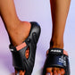 Black Kaelos comfort slides worn on feet, featuring embossed 'FASHION' and 'LIFE IS BEAUTIFUL' text and coral accent strap, with orange textured footbed and chunky sole.
