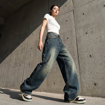 Kaelos high waisted wide leg jeans in vintage wash indigo, shown from a low angle in an urban setting to highlight the floor-grazing length and baggy streetwear silhouette.