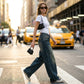 Kaelos high waisted wide leg jeans in vintage wash denim, side view of model walking in city showing the loose streetwear fit and floor-grazing length.
