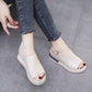 Creamy off-white Kaelos wedge sandals with a crossover peep-toe and adjustable slingback strap, shown worn with denim jeans.