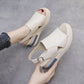 A pair of Kaelos creamy off-white wedge sandals shown from a three-quarter angle, featuring a crossover peep-toe vamp and adjustable slingback strap, with a grey accent stripe on the wedge.