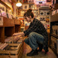 Kaelos wide-leg jeans in vintage wash denim worn by a woman crouching in a record store, styled with combat boots.