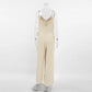 Back view of a Kaelum beige linen-blend wide-leg jumpsuit featuring spaghetti straps, a low V-neckline, and adjustable side ties. The relaxed silhouette has full-length, straight-leg pants and a matte, textured finish.