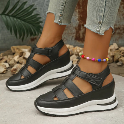 Model wearing Kaelum Classic Black platform wedge sandals with a closed round toe and three cut-out straps, paired with distressed jeans.