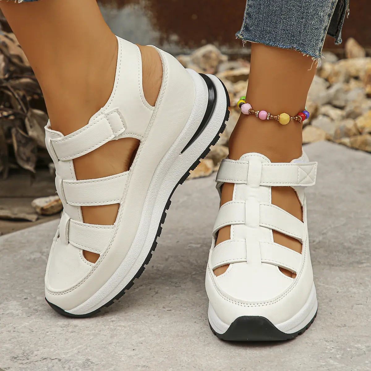 White Kaelum women's platform wedge sandals with cut-out straps and hook-and-loop closures, shown worn on feet in a casual outdoor setting.