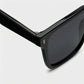 KAEON oversized square sunglasses in black, close-up view showing reinforced alloy hinge and signature metal temple accent.