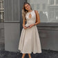 Model wears a natural beige linen blend sleeveless midi dress featuring a keyhole neckline with a single button and a flowing A-line skirt, standing in an urban setting.