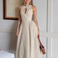 Woman wearing a sleeveless, natural linen-blend midi dress with a keyhole neckline and a gathered A-line skirt, set in a softly lit room.