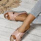 Close-up of women's pink Kalyx comfort wedge sandals with elegant criss-cross straps and micro-perforations, worn with jeans and a straw hat.