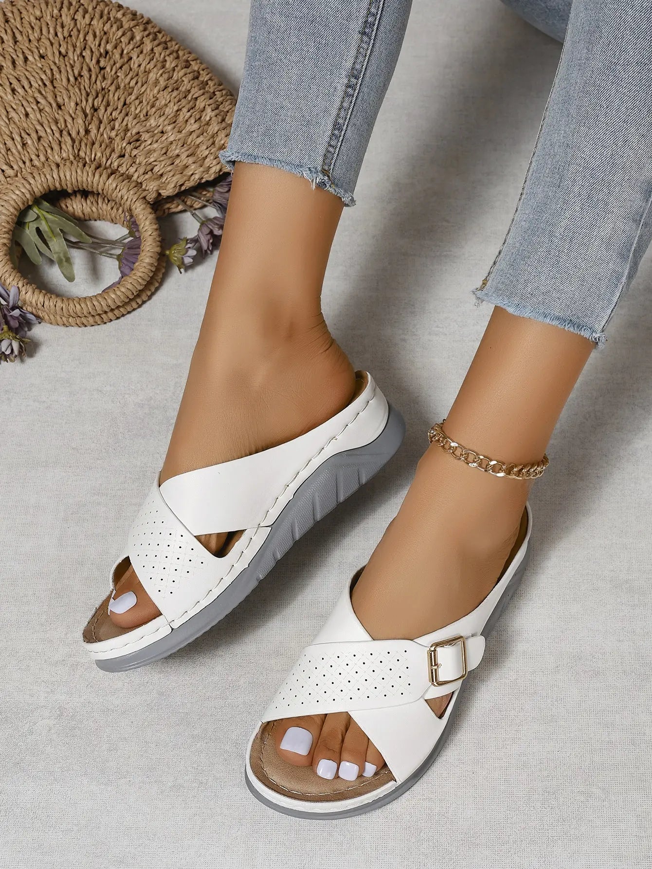 Kalyx white faux leather wedge sandals with elegant criss-cross straps and a gold buckle, shown on a model's feet in a bohemian summer lifestyle scene.