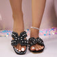 Black Kezia embellished flat sandals featuring intricate pearl and rhinestone detailing on a wide strap, worn by a model with white-toe nail polish and a delicate ankle bracelet.