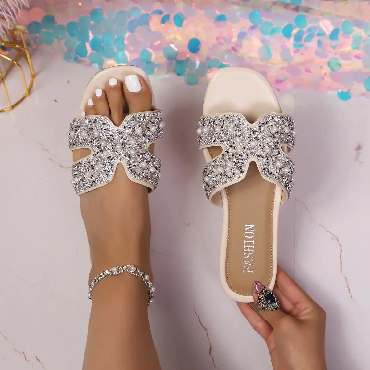 Kezia embellished flat sandals featuring pearl and rhinestone detailing on a single wide strap, shown on a foot with a square toe and subtle 'FASHION' insole branding.