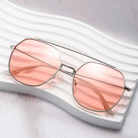 Khori silver metal double bridge aviator sunglasses with gradient pink lenses, presented at a three-quarter angle on a white textured display.