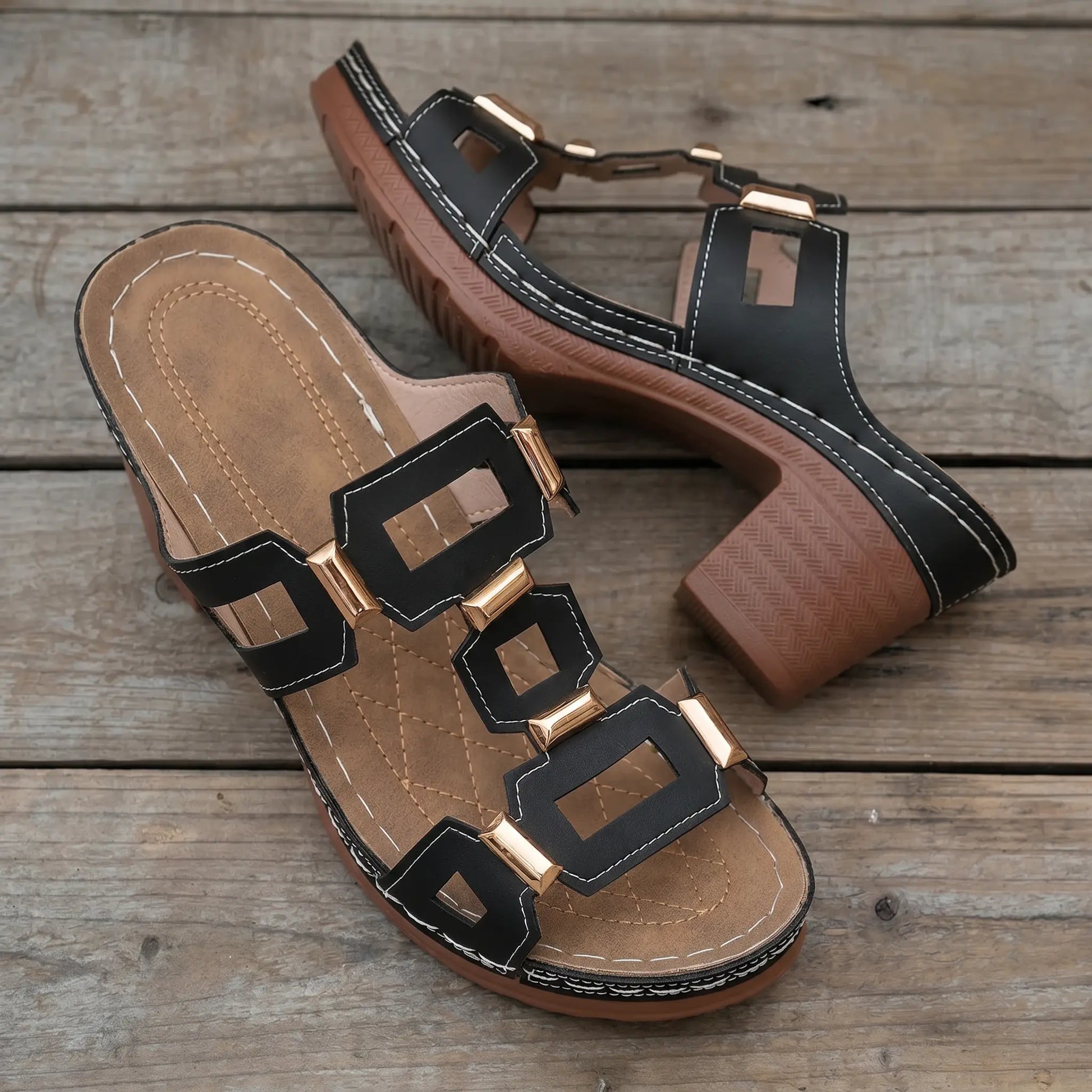 Black Khoros heeled slide sandals featuring a geometric gold-tone hardware strap and a chunky block heel with a visible platform.