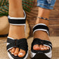 Women's black and grey woven textile platform sandals with a bow detail on the forefoot and adjustable hook-and-loop ankle straps, worn with denim jeans.