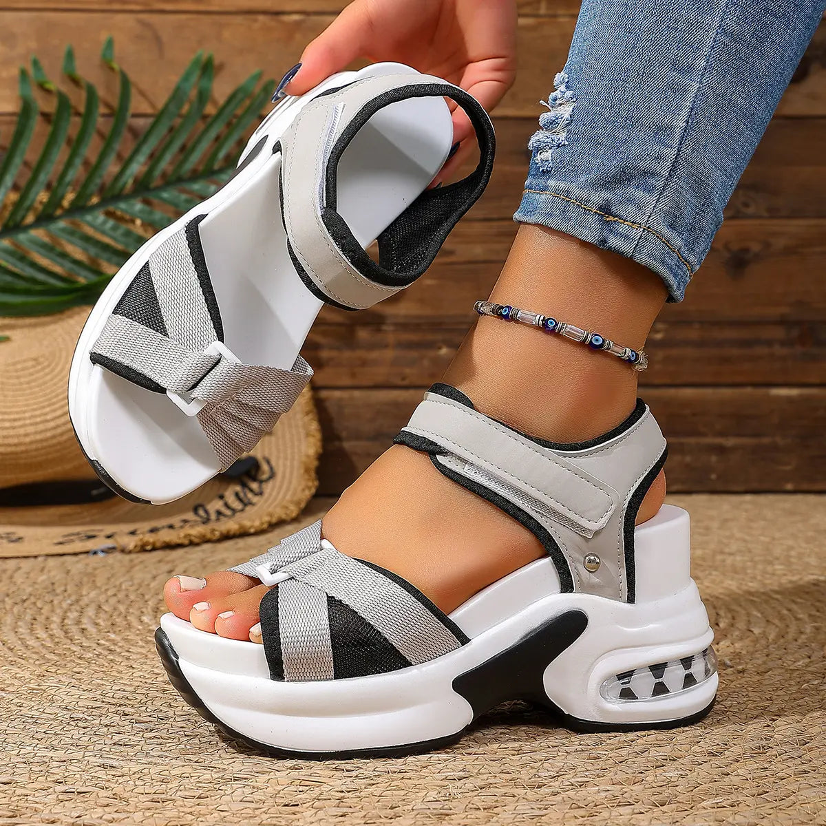 Close-up of women's black and grey woven textile strap platform sandals on a foot, showcasing the adjustable hook-and-loop ankle strap, layered white EVA midsole, and transparent air-cushion heel unit.