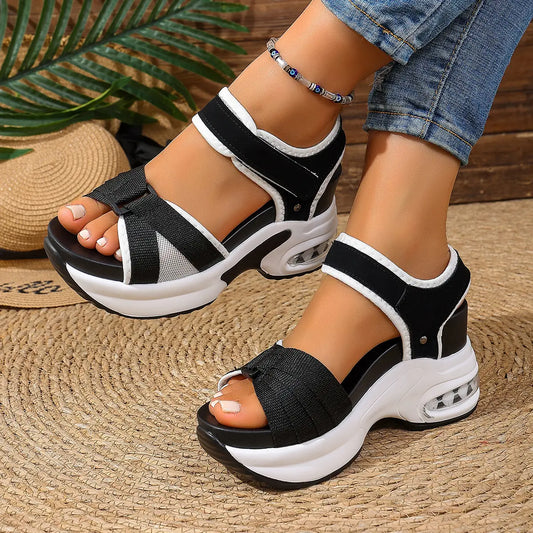 Women's black and grey woven textile platform sandals featuring a bow detail, adjustable hook-and-loop ankle straps, and a layered white sole with a visible air cushion heel.
