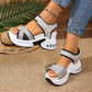 Women's black and grey woven textile platform sandals with a bow detail, white stacked sole, and visible air cushion heel, shown on a model in a casual, summery setting.