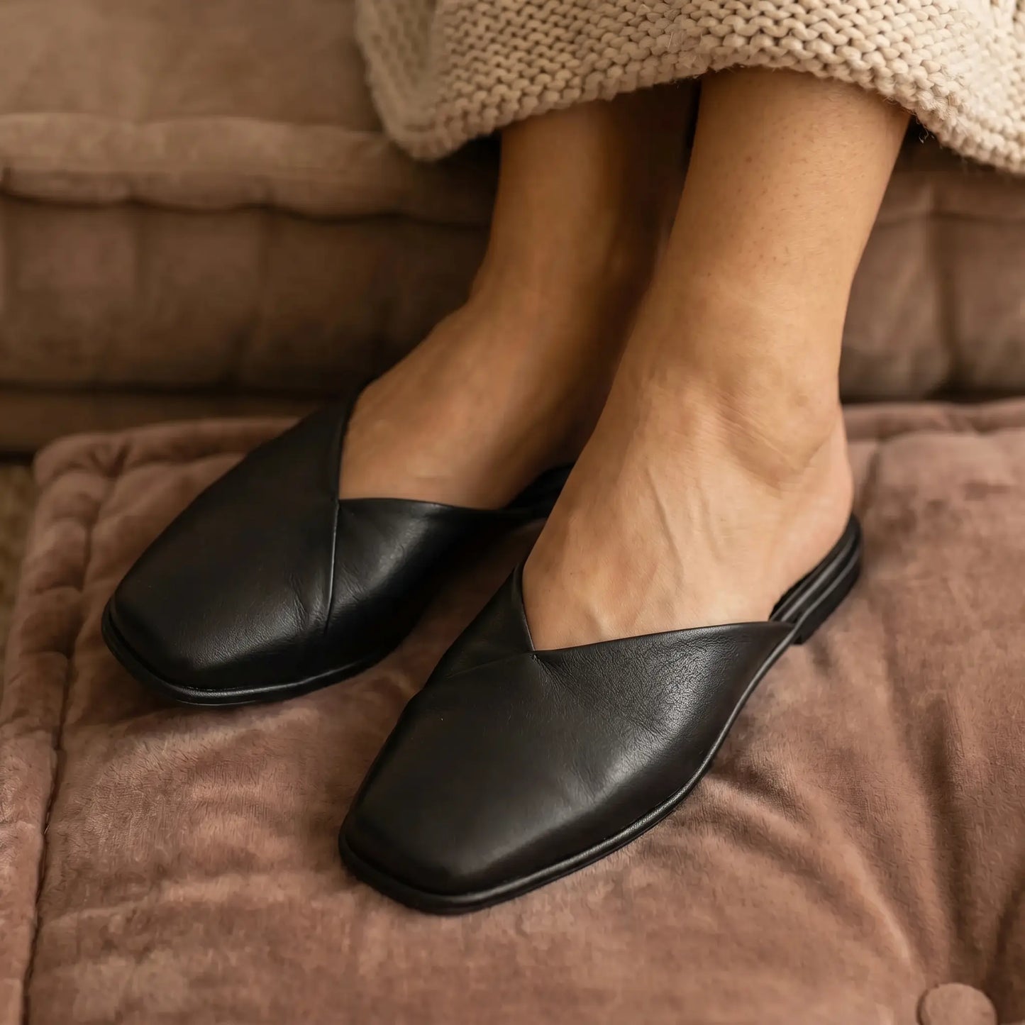 Khyren Midnight Black vegan leather mule flats with V-cut vamp and rounded square toe, worn effortlessly on feet in a relaxed setting.