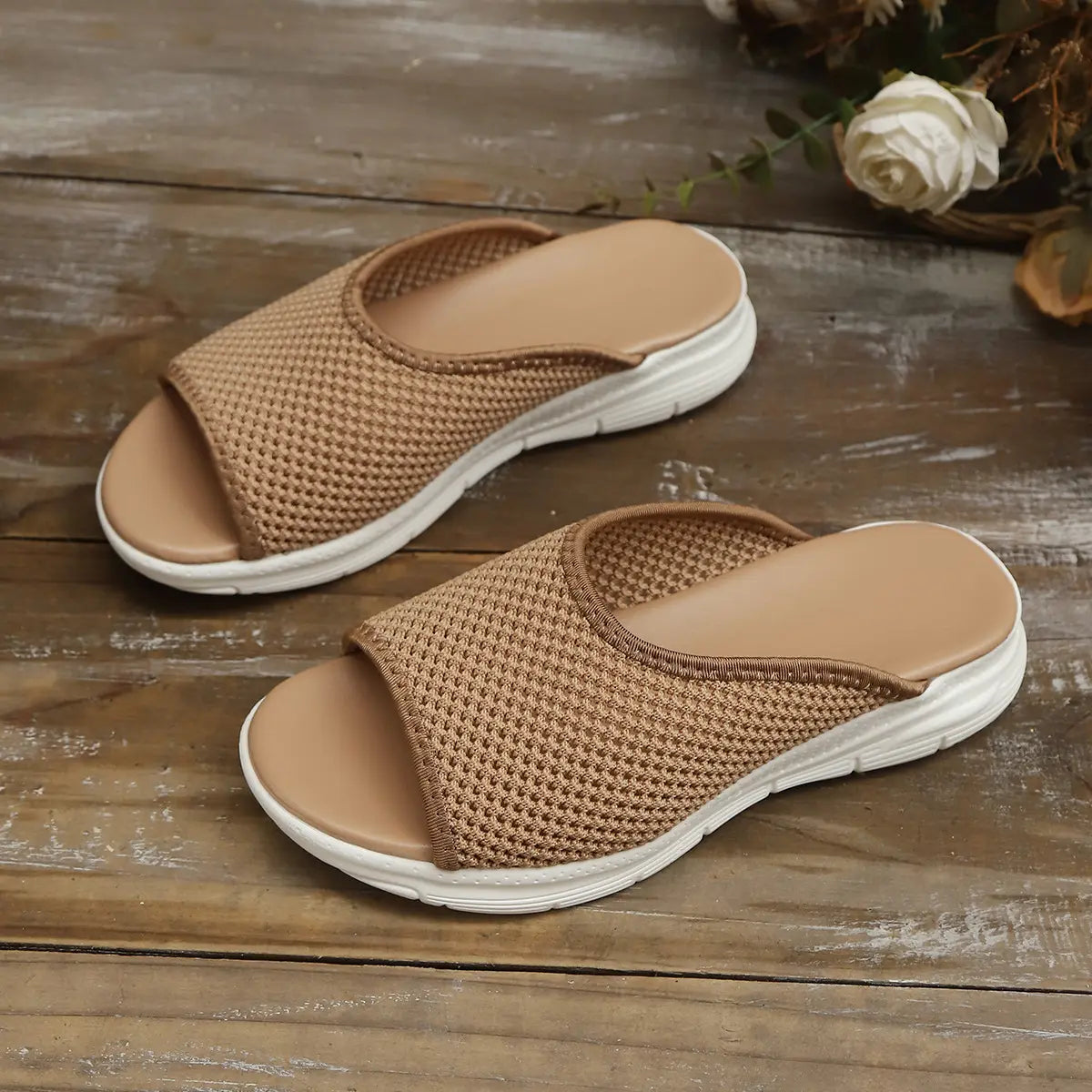 Kithra women's breathable knit slide sandals in soft khaki with a contoured tan footbed and layered white EVA sole, shown at a three-quarter angle on a wooden surface.