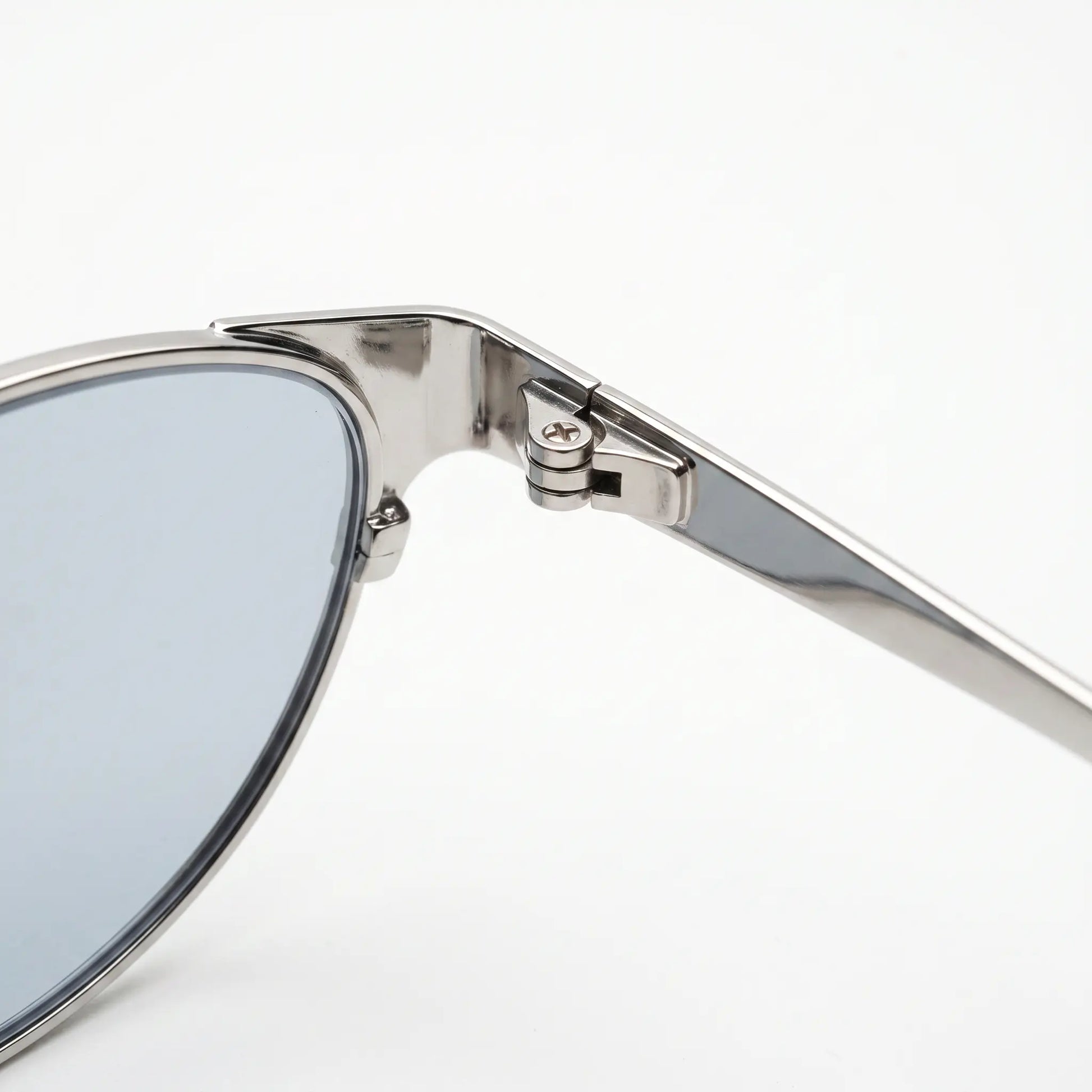 Kivago silver metal cat-eye sunglasses, showcasing the exquisite craftsmanship of the precision hinge mechanism and durable frame. A close-up view of the polished silver finish and light blue tinted lens.