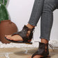 Dark brown matte PU leather gladiator sandals with lace-up ankle ties and a thong toe post, shown on a woman's feet paired with denim jeans.