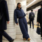 Kovara thermal quilted wide-leg trousers in navy blue, worn by a commuter in a subway station, showing the diamond stitch pattern and relaxed fit.