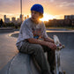 Kovari docker beanie in cobalt blue worn by a skateboarder sitting at a city skate park during sunset.