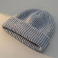 Kovari Docker Beanie fisherman hat in light grey ribbed knit, displayed flat showing the thick rolled cuff and soft texture.