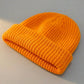 Kovari Docker Beanie fisherman hat in vibrant orange ribbed knit — three-quarter view showing the thick rolled cuff and structured crown.