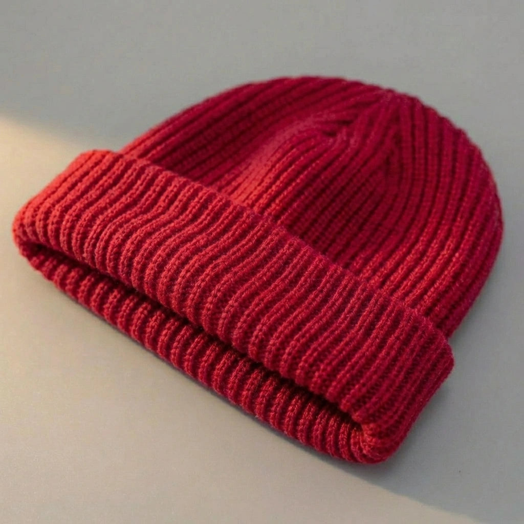 Kovari Docker Beanie in crimson red featuring a vertical ribbed knit texture and rolled cuff — angled view of fisherman style hat.