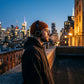 Kovari docker beanie fisherman hat in ribbed knit rust orange — side profile lifestyle view of man wearing headphones against a city skyline.