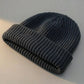 Kovari docker beanie fisherman hat in dark gray ribbed knit — three-quarter view showing rolled cuff and texture.