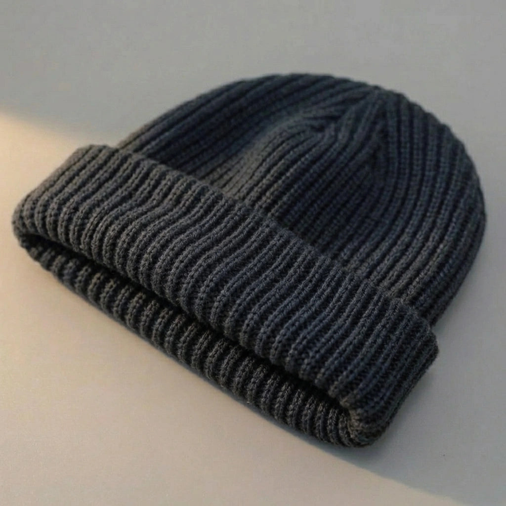 Kovari docker beanie fisherman hat in dark gray ribbed knit — three-quarter view showing rolled cuff and texture.