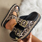 Women's Kovari leopard print platform slide sandals with antique gold double buckle detail, styled on a foot and held by hand against a textured neutral background.