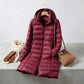 Kovera burgundy long puffer coat with hood, displayed with a scarf, gloves, and handbag in a styled lifestyle setting.