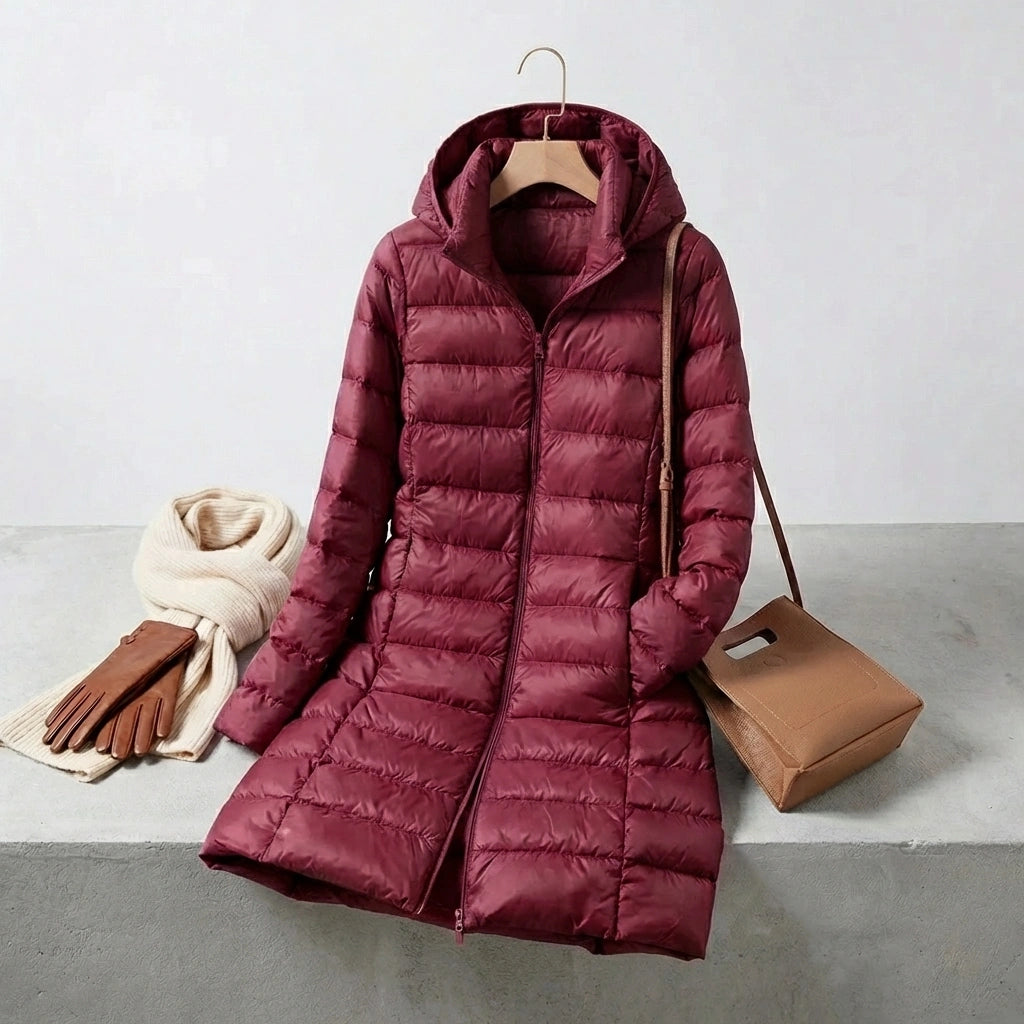 Kovera burgundy long puffer coat with hood, displayed with a scarf, gloves, and handbag in a styled lifestyle setting.