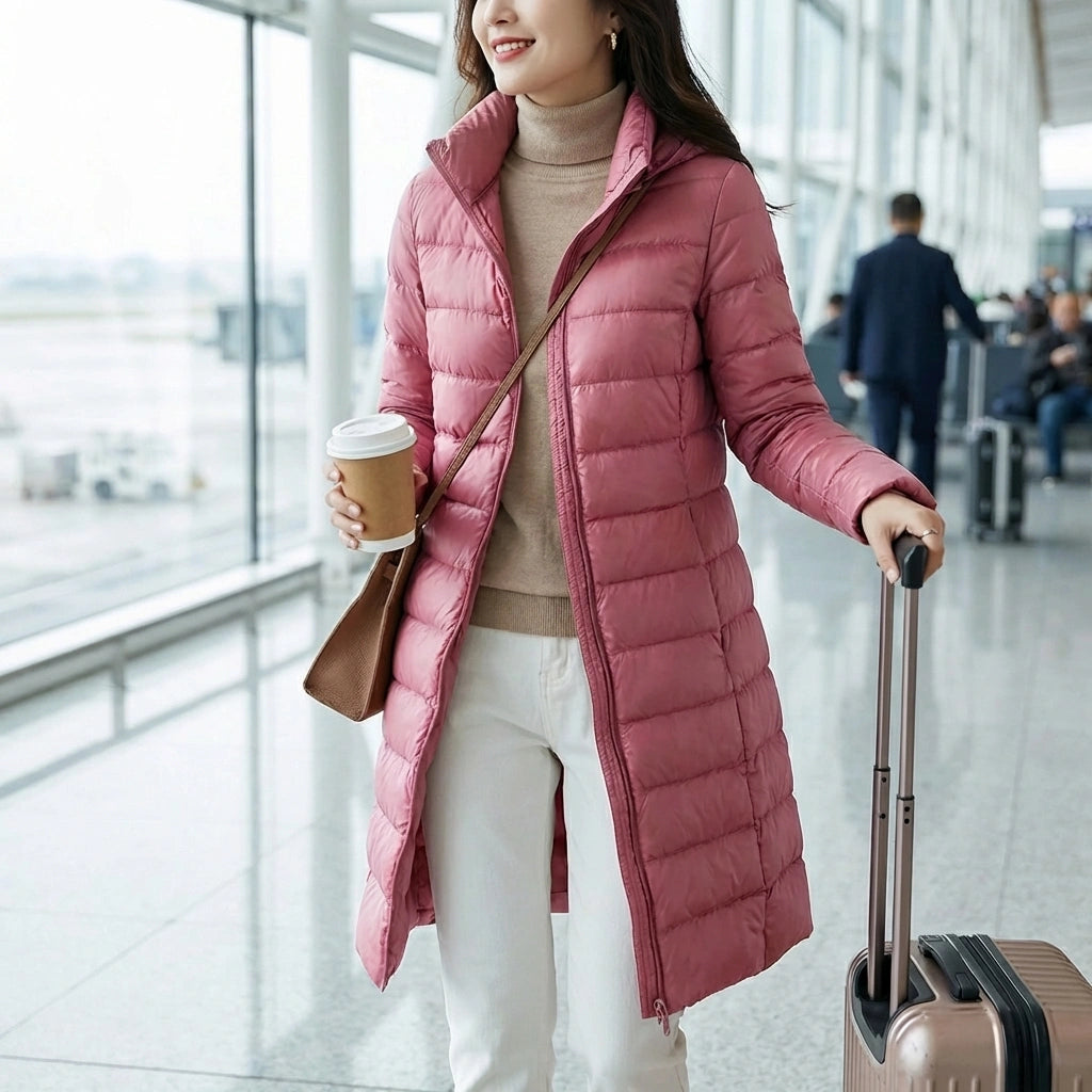 Kovera slim fit long puffer coat in soft rose pink worn by a woman in an airport terminal, showcasing the tailored silhouette and travel-ready style.
