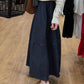 Kozira midnight A-line midi skirt with white polka dot pattern and distinct horizontal panel seam, worn by a model with a white sweater and tan clogs in an elegant indoor setting.