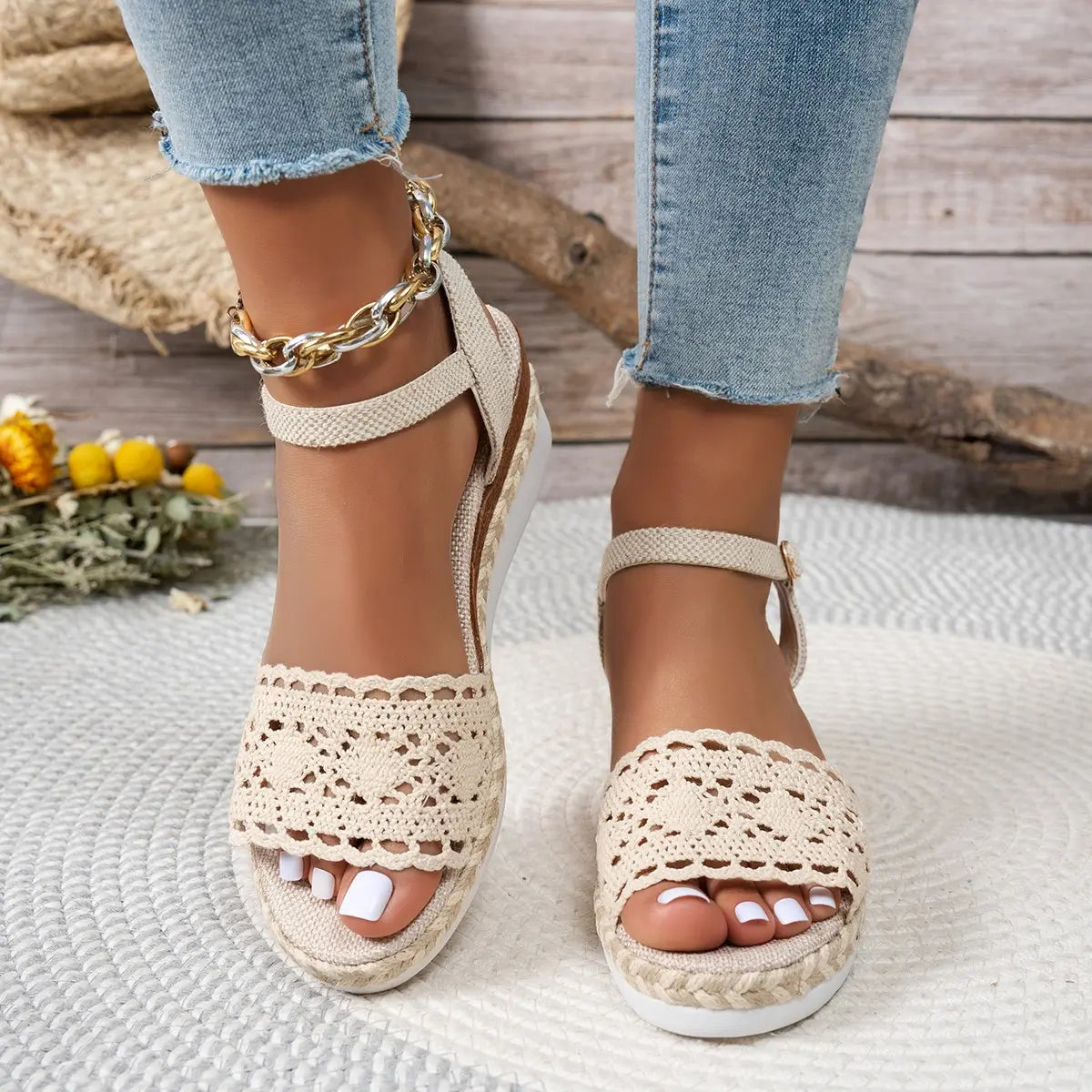 Women's beige espadrille wedge sandals featuring intricate crochet lace vamps, jute-wrapped wedge soles, and adjustable ankle straps worn with cropped denim jeans.