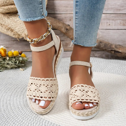 Women's beige espadrille wedge sandals featuring intricate crochet lace vamps, jute-wrapped wedge soles, and adjustable ankle straps worn with cropped denim jeans.